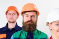 Builder near colleagues. Bearded labourer concept. Man with beard