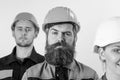 Builder near colleagues. Bearded labourer concept. Man with beard