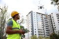 Builder operating drone with remote control at construction site. Aerial photography