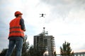 Builder operating drone with remote control at construction site. Aerial photography