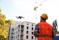 Builder operating drone with remote control at construction site. Aerial photography