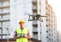 Builder operating drone with remote control at construction site. Aerial photography