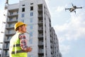 Builder operating drone with remote control at construction site. Aerial photography