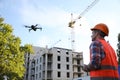 Builder operating drone with remote control at construction site. Aerial photography