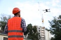 Builder operating drone with remote control at construction site. Aerial photography