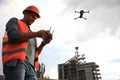 Builder operating drone with remote control at construction site. Aerial survey