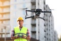 Builder operating drone with remote control at construction site, focus on quadcopter. Aerial survey