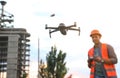 Builder operating drone with remote control at construction site, focus on quadcopter. Aerial survey