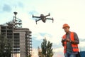 Builder operating drone with remote control at construction site focus on quadcopter. Aerial survey