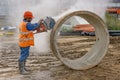 Builder in orange uniform with a concrete cutter