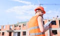 Builder orange vest and helmet works at construction site. Control construction process. Contractor control according to