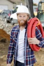 builder outdoors on construction site holding red pipe Royalty Free Stock Photo