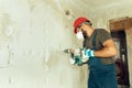 Builder with perforator drills holes in concrete wall Royalty Free Stock Photo