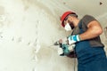 Builder with perforator drills holes in concrete wall Royalty Free Stock Photo