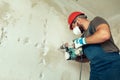 Builder with perforator drills holes in concrete wall Royalty Free Stock Photo