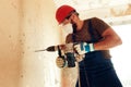 Builder with perforator drills holes in concrete wall Royalty Free Stock Photo
