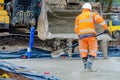 Builder pouring ground floor slab of a new house with wet ready-mix concrete, levelling it and checking level