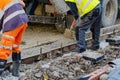 Builder pouring ready-mix concrete into formwork, levelling it and checking level