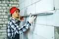 Builder pressing construction ruler to interior wall checking its quality