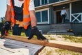 Builder pressing tape measure to board outdoors