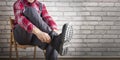 Builder putting on shoes for work near brick wall. Royalty Free Stock Photo