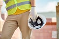 Builder in a reflective waistcoat carrying his hardhat