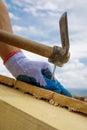 Builder`s hands hammering nail into wood