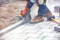 The hands of a builder with the help of a grinder cut the paving slabs against the backdrop of the work site. Close-up, blurred Royalty Free Stock Photo