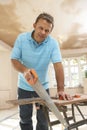 Builder Sawing Wood On Workbench