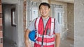 builder smiling confident holding hardhat at construction site Royalty Free Stock Photo