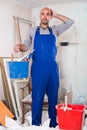 Builder is standing with bucket and putty knife and thinking about where he should start Royalty Free Stock Photo