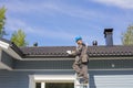 The builder stands on a ladder and uses tape measure in Finland.