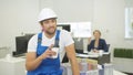 Builder talks something on camera with smile and drinks coffee
