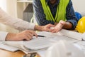 Builder team, hand of asian, caucasian young engineer, architect two man are discussing construction drawing on blueprint follow Royalty Free Stock Photo