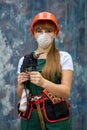 Builder with tools. Woman in green coverall and protective mask holding drill machine on abstract background Royalty Free Stock Photo