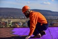 Builder use roof tile. professional master repair roof. Flat roof installation. Roofer in special protective work wear Royalty Free Stock Photo