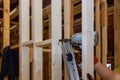 Builder uses an air hammer to secure wooden beams to a house framework