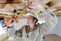 Builder using cordless screwdriver on wooden ceiling joist