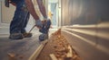 A builder using a nail gun to secure new baseboards along the hallway of the office building Royalty Free Stock Photo
