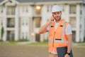 Builder using phone. Builder at construction site. Buider with helmet on construction outdoor. Worker at construction