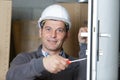 Builder using screwdriver to adjust door hinge Royalty Free Stock Photo