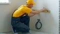 Builder using a spirit level to measure a wall.