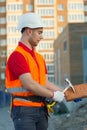 Builder vest and helmet construction site holding brick and hammer in hands Royalty Free Stock Photo
