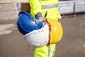 builder wearing a hi-viz reflective suit gives a choice of helmets. Always use safety and personal protective equipment for