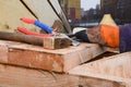 A builder in work gloves puts tools. Hammer, pliers, rubber mallet and tongs on a wooden staircase.