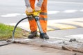 Road worker breaking asphalt pavement with pneumatic construction hammer