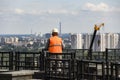 Builder worker in a helmet looks at the city with cranes and houses.