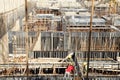 Builder worker knitting metal rods bars into framework reinforcement for concrete pouring at construction site