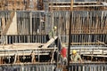 Builder worker knitting metal rods bars into framework reinforcement for concrete pouring at construction site