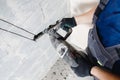 Builder worker man with hammer drill perforator equipment making hole in gray wall construction Royalty Free Stock Photo